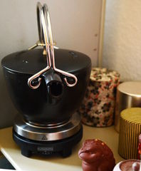 emaillierter Eisenkessel auf Kochplatte, diverse Caddies und ein Teetier